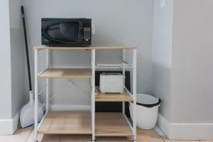 a small shelf with a microwave and a computer on it at NEW Renovated Cozy 2 Br in Uptown Saint John Location Coffee in Saint John
