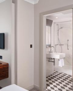 a white bathroom with a sink and a tub at Strand Palace in London