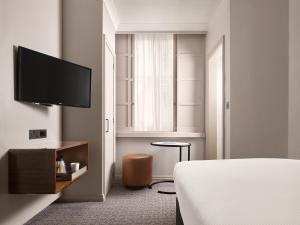 a bedroom with a bed and a flat screen tv at Strand Palace in London