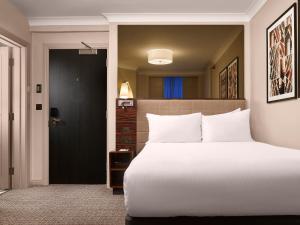 a bedroom with a large white bed and a black door at Strand Palace in London