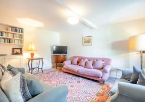 a living room with a pink couch and a tv at Point Cottage in Blakeney