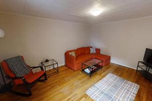 a living room with an orange couch and two chairs at Charming Home Heart Of Uptown! Location! Coffee! in Saint John