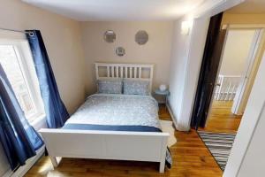 a white bed in a room with blue curtains at Charming Home Heart Of Uptown! Location! Coffee! in Saint John