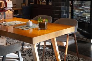 een houten tafel met stoelen en een tafel met bloemen erop bij Hotel Ma Belle in Pristina