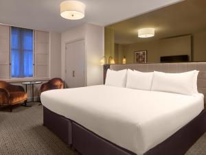 a large white bed in a hotel room at Strand Palace in London