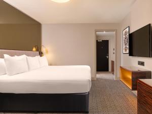 a hotel room with a bed and a flat screen tv at Strand Palace in London