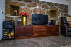 a living room with a tv and a stone wall at Fraga Douro House, Douro Valley in Resende