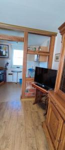 ein Wohnzimmer mit einem TV und einem Schreibtisch mit einem TV in der Unterkunft Ferienwohnung Weise in Grillenberg