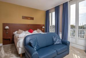 sypialnia z łóżkiem i niebieską kanapą w obiekcie Hôtel Le Yachtman, The Originals Collection w La Rochelle