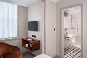 a bathroom with a television and a sink at Strand Palace in London