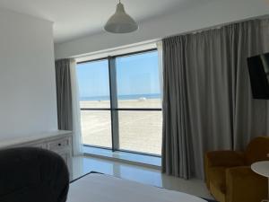 a living room with a large window with a view of the beach at Beach Rooms Roberta in Mamaia