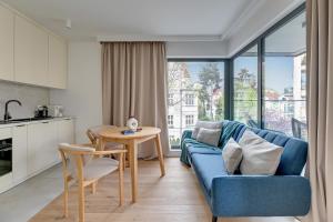 a living room with a blue couch and a table at Monte Cassino Apartments by Blue Mandarin in Sopot