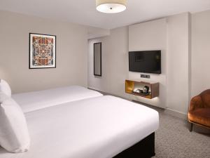 a hotel room with a bed and a tv at Strand Palace in London