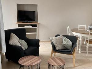 sala de estar con silla y TV en Le grenier de la Floye, en Biesmerée