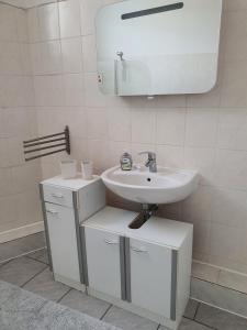 La salle de bains blanche est pourvue d'un lavabo et d'un miroir. dans l'établissement Koala-1-5-Personen, à Brunsbüttel