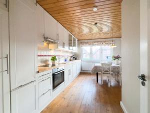 cocina con armarios blancos y techo de madera en Backhus Nordkampen, en Walsrode