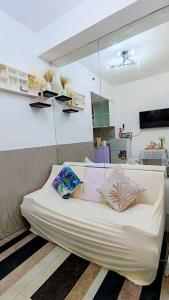 Sofá blanco en una habitación con espejo en #68 The Grass Residence T1B-18th, en Manila