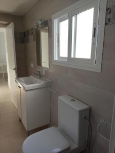 ein Bad mit einem WC, einem Waschbecken und einem Fenster in der Unterkunft Casa Correos in Medina-Sidonia