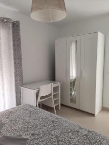 a bedroom with a bed and a desk and a cabinet at Casa Correos in Medina Sidonia