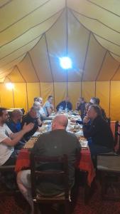 a group of people sitting at long tables in a tent at camp erg znaigui in Taouz