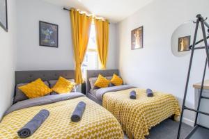 2 camas individuales en una habitación con cortinas amarillas en Open Mind Property - Cosy Flat in Southsea en Portsmouth