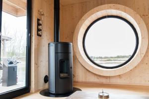 a woodburning stove in a room with a round window at Luxus-Hausboot DIVA mit Kamin in Hamburg