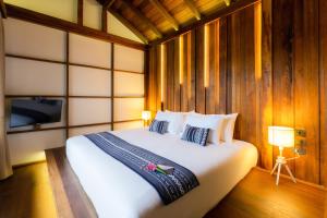 a bedroom with a large white bed and a tv at Athita The Hidden Court Chiang Saen Boutique Hotel in Chiang Saen +76 photos
