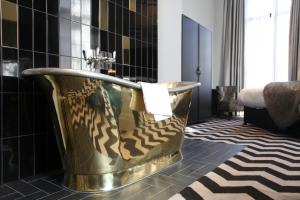 a gold tub in a bathroom with black tiles at Hotel Gotham in Manchester