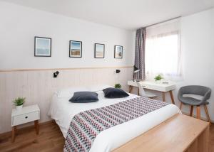 ein Schlafzimmer mit Bett, Schreibtisch und Fenster in der Unterkunft Hôtel - Restaurant Atlantide in Biscarrosse