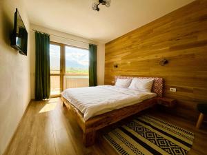 a bedroom with a bed with wooden walls and a window at Casa Aluna Duo in Sohodol
