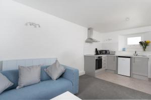 a living room with a blue couch and a kitchen at Beautiful 1 bedroom ground floor new apartment in old Cornwall in St. Just