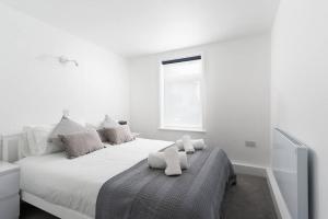 a white bedroom with a bed with two white towels at Beautiful 1 bedroom ground floor new apartment in old Cornwall in St. Just