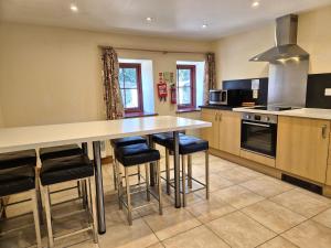 a kitchen with a large counter and stools at Kestrel Farmhouse in Llandovery
