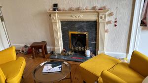 a living room with a fireplace and yellow chairs at Palm Tree Apartment- Period Home with Cat in Edinburgh