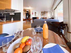 a table with a bowl of fruit and a bottle of orange juice at L'Archimède - Parking privé in Versailles +71 photos