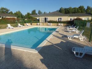 a swimming pool with lounge chairs and a house at Terres de France - Les Hameaux de Miel in Beynat