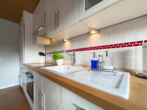 cocina con fregadero blanco y azulejos rojos y blancos en Backhus Nordkampen, en Walsrode