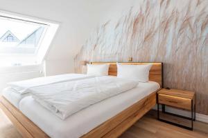 a bedroom with a large white bed with a wooden headboard at Käpt'n Nelson, App 13 in Wenningstedt