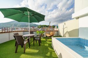 a patio with a table and an umbrella on a balcony at Browndot Samcheonpo in Sacheon