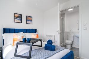 a bedroom with a bed with a table and a toilet at Brand New Luton Apartments in Luton