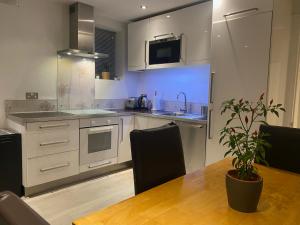 Luxury Putney Riverside Apartment في لندن: مطبخ مع طاولة خشبية مع نبات الفخار