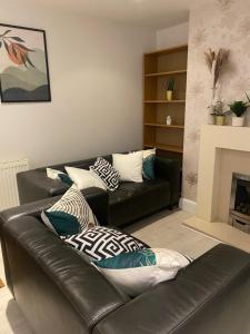 sala de estar con sofá de cuero negro con almohadas en Luxury Putney Riverside Apartment, en Londres
