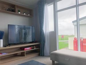 sala de estar con TV y ventana grande en A Sea View Scene - Ocean Edge Holiday Park, en Heysham