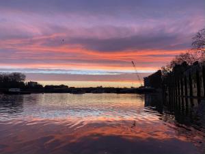 Luxury Putney Riverside Apartment في لندن: تجمع المياه مع غروب الشمس في الخلفية