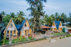 a row of houses on the beach with palm trees at Agonda Palm Beach Resort in Agonda