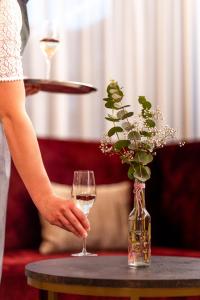 une femme tenant un verre de vin sur une table dans l'établissement Hotel Krone Langenegg, à Langenegg