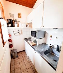 a small kitchen with a sink and a microwave at La Tiloé des dunes ~ T3 centre de la Palmyre in Les Mathes
