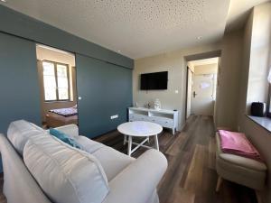 a living room with a white couch and a tv at Antica Stazione in Guebwiller