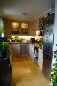 a kitchen with stainless steel appliances and wooden cabinets at Cozy room in a house with a garden on the island of Askøy, near Bergen in Askøy +12 photos