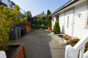 a driveway leading to a house with flowers and plants at Cozy Room with Garden on Askøy Island, Close to Bergen in Askøy